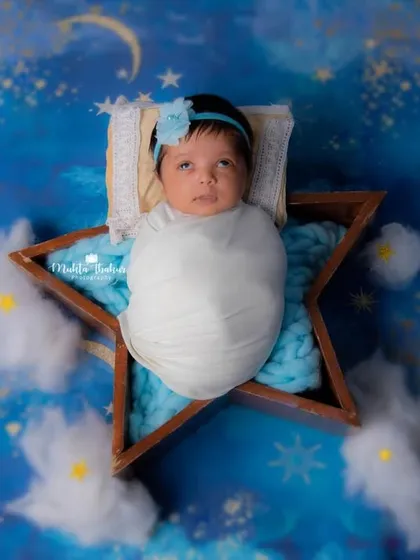 "That eye roll expression!" This newborn is already a star, posing in a star-shaped prop against a dreamy, celestial sky backdrop.