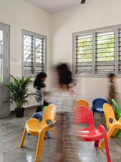 Movement and energy are vital in a children's space. This image captures the dynamic flow within the Anganwadi classroom, made possible by an open layout and movable furniture. The large doors and windows connect the indoors with the outside, creating a bright and airy atmosphere for kids to learn and play.