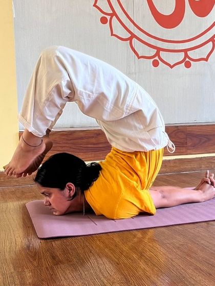 A student demonstrates an advanced variation of Salabhasana (Locust Pose), a powerful backbend that strengthens the entire back of the body and improves posture.