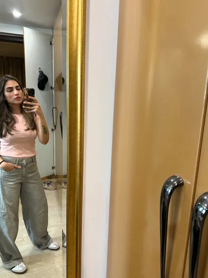 A simple pink t-shirt paired with grey pinstripe baggy jeans. This shows how to play with proportions for a modern look.