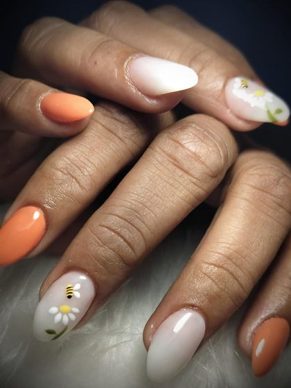 Spring into beauty with this adorable nail art. I combined a cheerful orange polish with accent nails featuring a cute, hand-painted bee and daisy design.