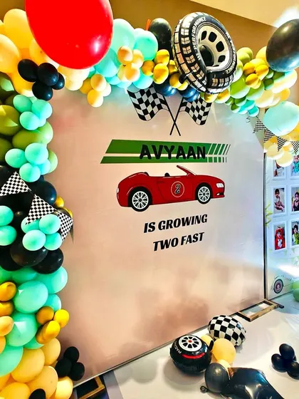 The custom backdrop for Avyaan's "two fast" birthday party, framed by a colorful balloon garland with checkered flag details.