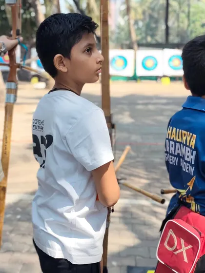 A young archer observing the competition. Learning by watching others is an important part of development.