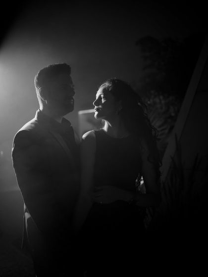 A dramatic black and white silhouette created with a single light source. This artistic technique focuses on the couple's profiles and the space between them, creating a powerful, moody image.