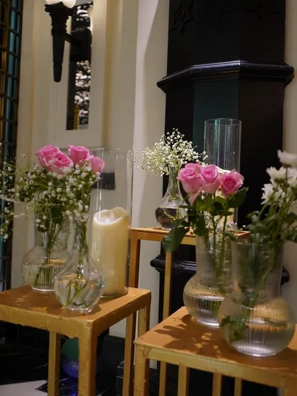 Simple, elegant details like these glass vases with pink roses and baby's breath can add a soft, romantic touch to any corner of the wedding venue.