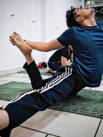 A student practices a variation of Eka Pada Rajakapotasana, focusing on hip opening and spinal extension.