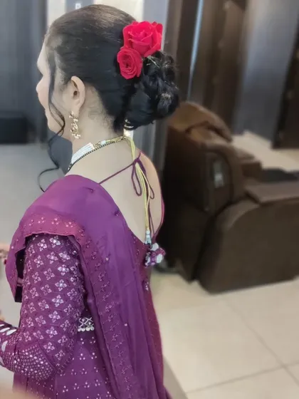 A back view of a party hairstyle, showing a neat bun decorated with fresh red roses. This style is elegant and keeps hair perfectly in place throughout the event.