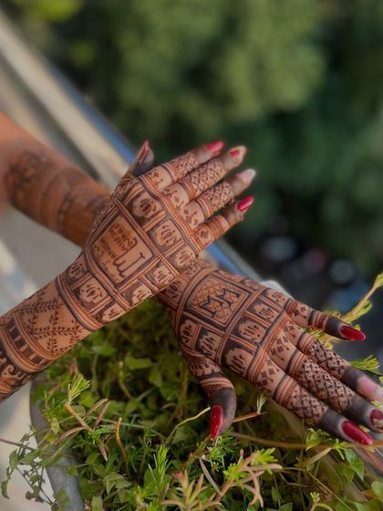 An outdoor shot of the back-of-hand design, with the natural greenery complementing the henna.