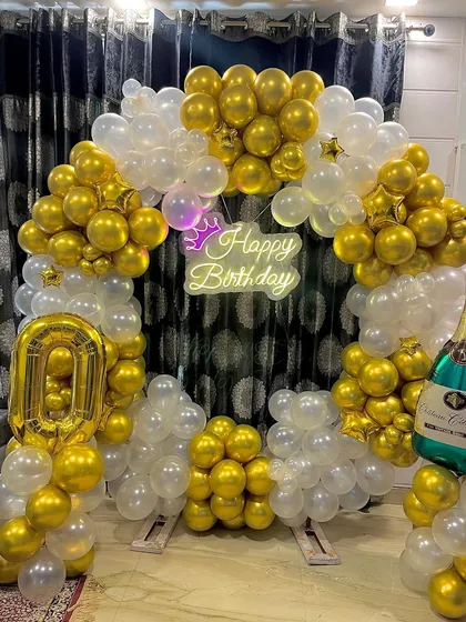 The gold and white balloon arch with a 'Happy Birthday' neon sign, ready for the party.