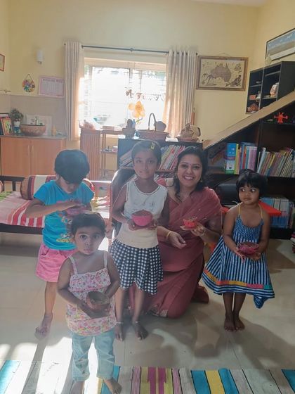 The storyteller poses with the children and their painted coconut shell creations.