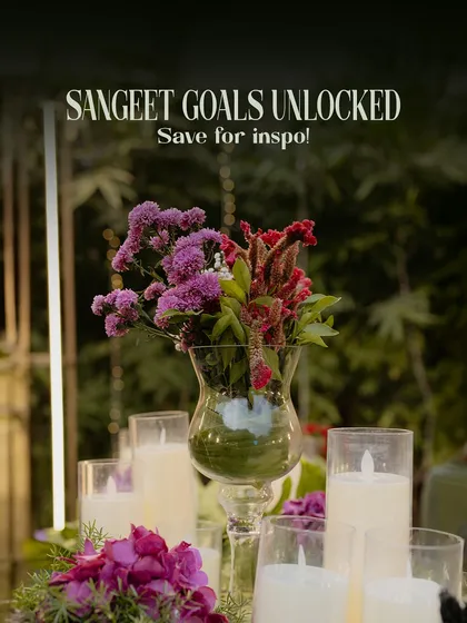 A close-up of the elegant centerpiece details for the Sangeet. The combination of fresh flowers and candles adds a touch of romance and sophistication to the guest tables.