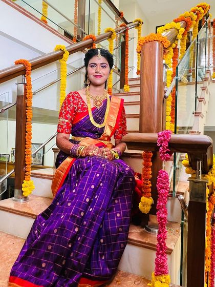 Posing on the beautifully decorated stairs, my client looks absolutely regal. This shot captures the elegance of her purple silk saree and the flawless finish of her makeup.