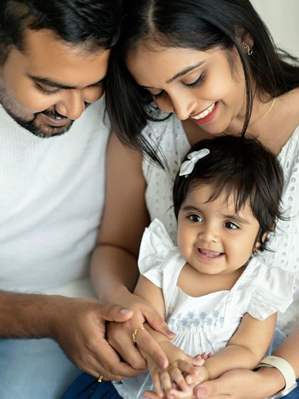 A beautiful family of three, with their adorable daughter smiling for the camera.