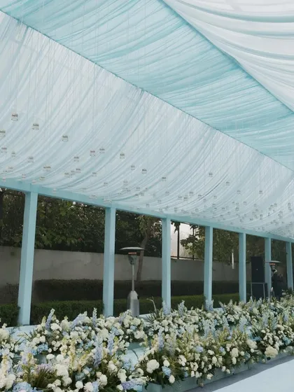 The walkway for the Anand Karaj ceremony is lined with lush arrangements of white flowers with hints of blue, creating a beautiful and respectful path for the proceedings.