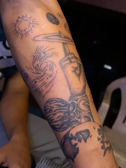 This angle highlights the integration of different styles within one sleeve, from the shaded planet at the bottom to the line-work galaxy and sun at the top.