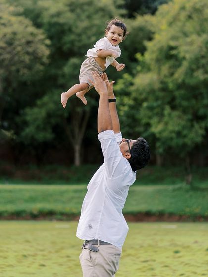 A father lifting his son in the air against a backdrop of green trees. A classic shot that captures pure joy.