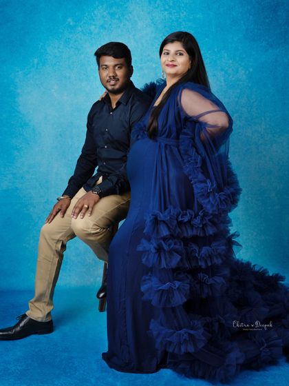 A stylish and confident pose from this expecting couple. Her blue gown and his relaxed posture create a cool, modern vibe.