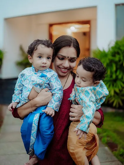 Capturing the bond between a mother and her children is a privilege. This outdoor portrait shows a mother holding her twin boys, dressed in traditional attire, creating a warm and authentic family moment.