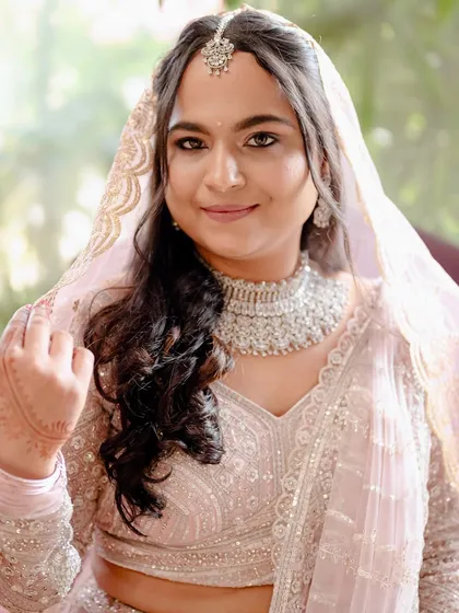 A vision in baby pink. Madhura's wedding lehenga was perfectly paired with fresh, rosy makeup and a soft, flowy hairstyle, creating a look of timeless elegance for her special day.