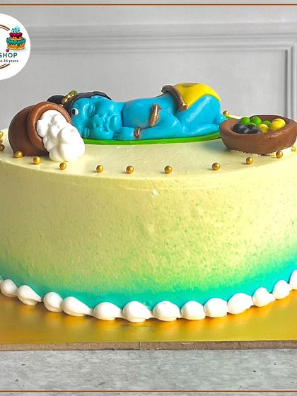 Another view of our adorable sleeping baby Krishna cake, showing the delicate details like the golden beads and the smooth buttercream finish.