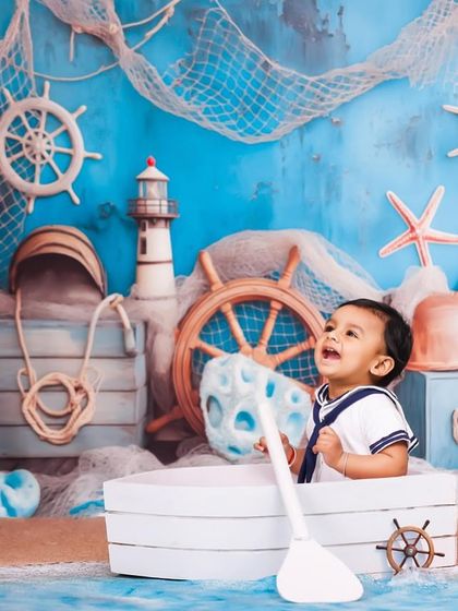 A joyful moment from my nautical-themed shoot. This little sailor is having a great time in his boat, surrounded by a detailed set with a ship's wheel, netting, and a lighthouse.