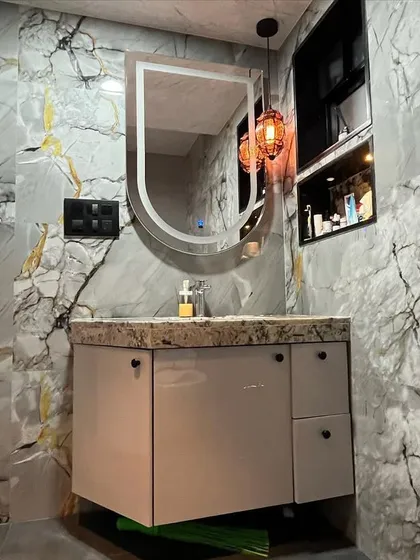 A detailed shot of the vanity area, highlighting the marble-patterned countertop and the simple, elegant design of the floating cabinet and mirror.