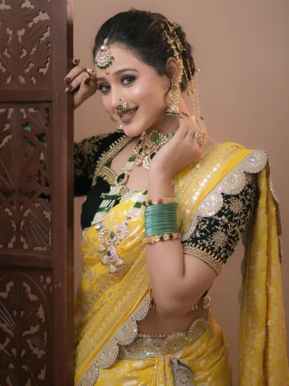 A stunning Maharashtrian makeup look with a yellow saree and contrasting black blouse. The makeup is kept radiant and fresh.