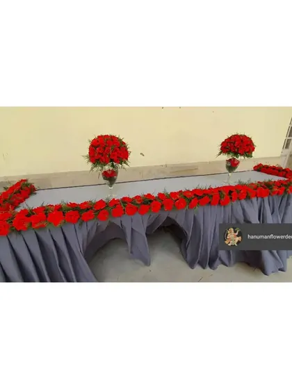 A long table at the NLU convocation, lined with a runner of red roses and featuring two matching centerpieces. This kind of floral table dressing is perfect for a head table or registration desk.