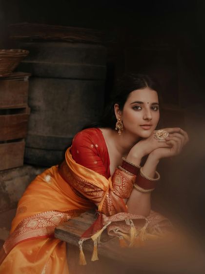 A thoughtful and poised portrait. The model rests her chin on her hands, looking directly at the camera with a calm and confident expression.