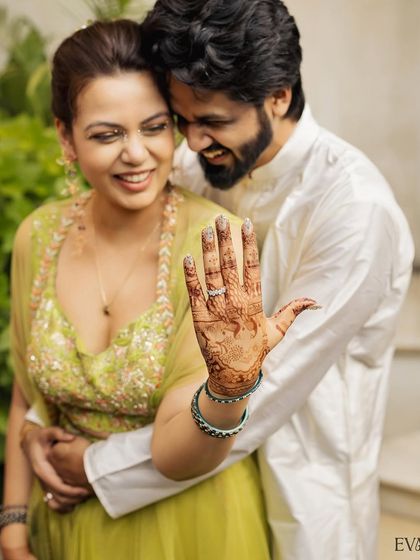 The bride proudly shows off her beautiful Mehendi design and engagement ring, a classic and happy shot from the celebration.