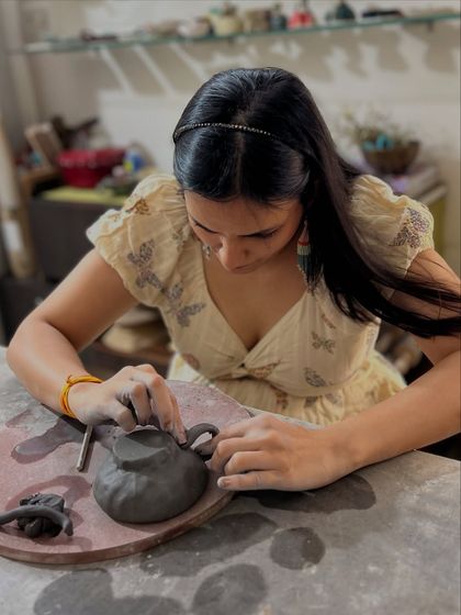 Carefully attaching a handle to a hand-built teapot. A clay date is a chance to learn a new skill together and encourage each other along the way.