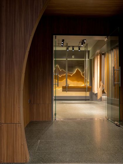 The entrance view of the veneer showroom, where a curved wood-paneled wall creates an inviting and organic flow into the space. The design immediately immerses visitors in a world of wood.