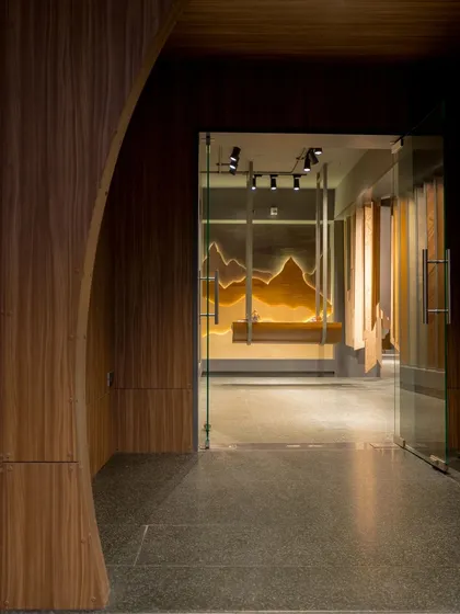 The entrance view of the veneer showroom, where a curved wood-paneled wall creates an inviting and organic flow into the space. The design immediately immerses visitors in a world of wood.