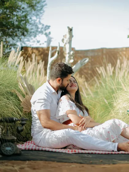 A sweet and romantic moment during a picnic-themed shoot, with the couple sharing a close embrace in a field of tall grass.