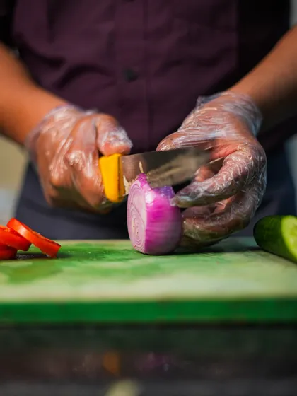 Freshness starts with the ingredients. Here, one of our chefs is carefully slicing fresh vegetables, a fundamental step in our process of creating delicious and healthy meals.