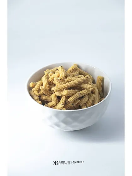 A minimalist shot of Murukku, a classic Indian snack, in a simple white bowl. The high-key lighting and clean background put all the focus on the texture of the snack itself.