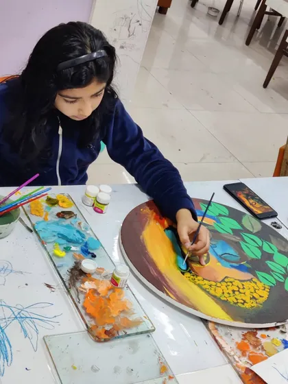 Multiple students are seen working on their own interpretations of Buddha paintings, showcasing a calm and focused studio environment.