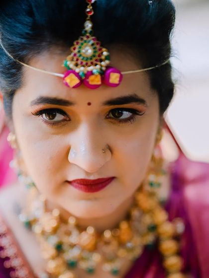 A powerful close-up portrait of the bride. This highlights the precision of the eye makeup and the rich lip color, creating a captivating and intense look.