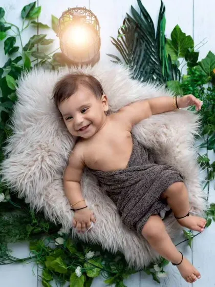 A relaxed 5-month-old baby in a cozy nest surrounded by greenery. This setup is great for younger babies who are not yet sitting up on their own.