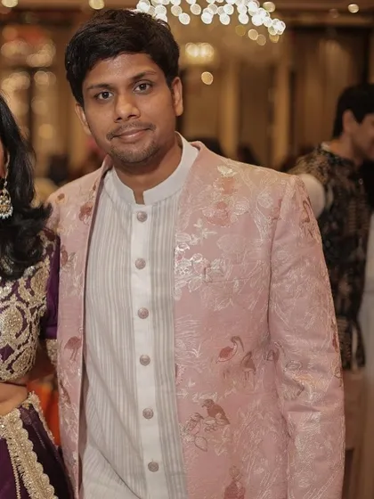 A client wearing a beautiful pink brocade indo-western jacket. The subtle pattern and soft color make it a perfect choice for daytime wedding festivities.