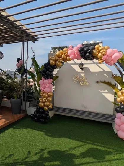 For a 'Bride to Be' party, I created this stylish balloon arch on a terrace. The black, pink, and gold color scheme and a custom neon sign make for a chic and fun celebration space.