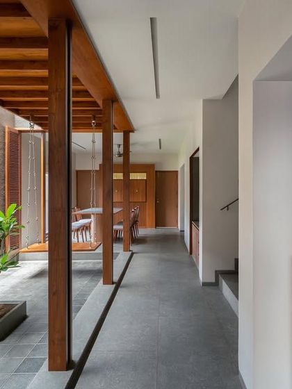 Inside the 'H-House', a linear courtyard with wooden columns defines the circulation path, bringing light and a connection to nature into the narrow plot.