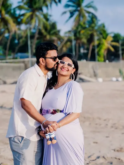 A playful and sweet kiss on the cheek. This happy couple enjoys a lighthearted moment during their sunny beach maternity shoot.