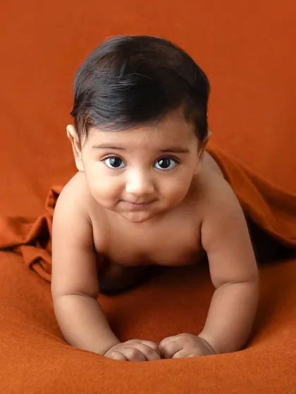 A six-month-old baby in a classic tummy-time pose. Their strength and curiosity are on full display, making for a powerful and adorable portrait.