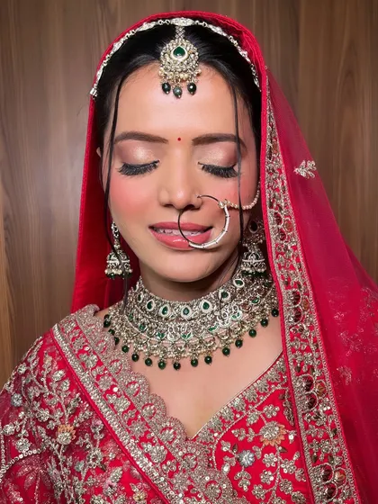 The complete look for my stunning bride in her red lehenga. The makeup is balanced, with glowing skin, defined eyes, and a soft lip color that completes the traditional ensemble.