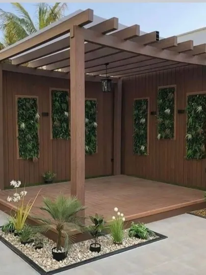 This design combines a wooden pergola with a raised deck and integrated vertical garden panels. It creates a self-contained, semi-private outdoor room.