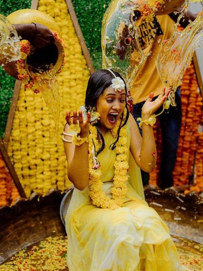 The highlight of the Haldi ceremony. The bride's expression is priceless as she gets showered with water, surrounded by our vibrant yellow floral decor.