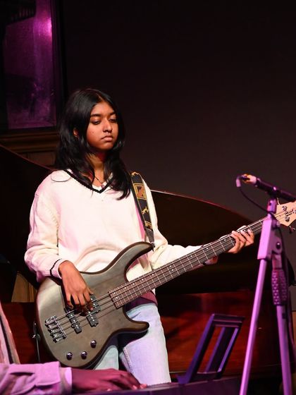 Our bass guitar student holding down the rhythm for her band. We offer specialized lessons for bass guitar, an essential part of any rock or pop ensemble.