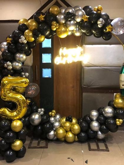 A bold and celebratory 45th birthday setup in black, gold, and silver. The champagne bottle balloon adds a fun, festive element to the circular balloon arch.