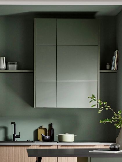 The grid-like design of the upper cabinets in metallic green creates a unique geometric feature, complemented by open shelving for a balanced look.